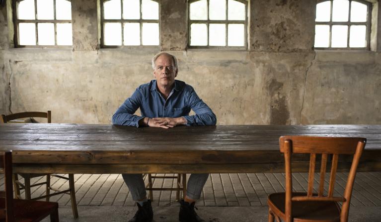 Stefan Stasse zit achter een houten tafel