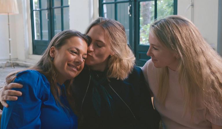 drie vrouwen geven elkaar een knuffel op de bank