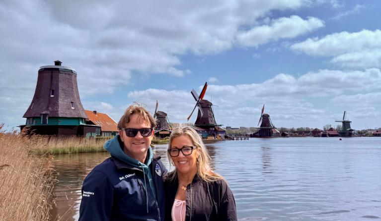 Man en vrouw staan naast elkaar voor Hollandse molens