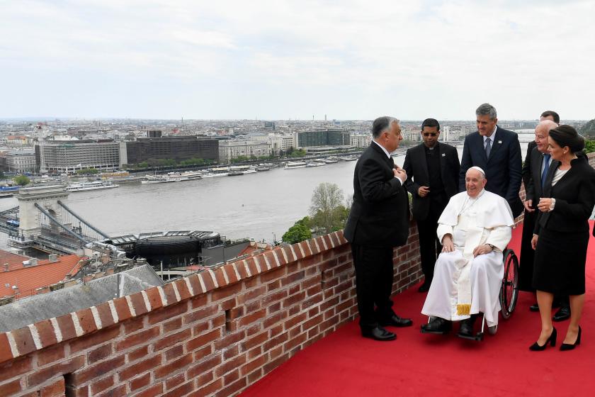 This photo taken and handout on April 28, 2023 by The Vatican Media shows Pope Francis, seated in a wheelchair, overlooking the city with Hungary's President Katalin Novak (R) and Hungary's Prime Minister Viktor Orban (L) after a meeting with the authorities, civil society, and the diplomatic corps in the former Carmelite Monastery in Budapest, Hungary, during his second visit to Hungary in less than two years. The Pope will meet refugees, believers, students, church and state leaders during his tree-day tr