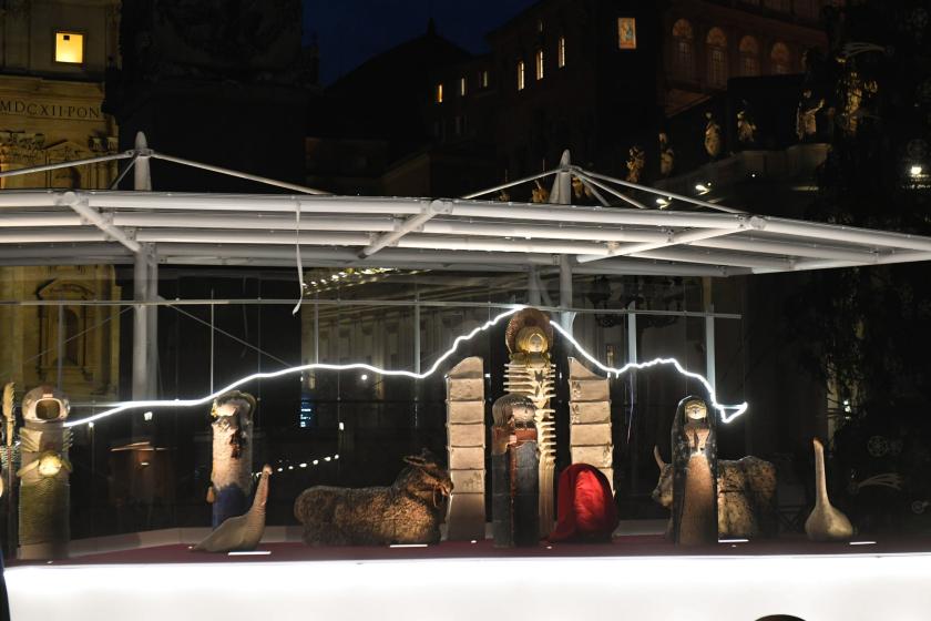 This picture taken at nightfall on December 11, 2020, shows a part of the crib during its official inauguration and the Vatican's Christmas tree at St. Peter’s Square in the Vatican. Near monumental nativity scene, made up of larger than life ceramic statues, from the village of Castelli, in Abruzzo region of Italy, is the Christmas tree, a large spruce tree 28 metres tall and with a diameter of about 70 centimetres, which this year is set up in St Peter's Square, came from one of the most luxuriant areas of Slovenia, the southeastern area, precisely from the municipality of Kocevje, on the Rinza river. Andreas SOLARO / AFP Vaticaanse keramiek kerststal 2020