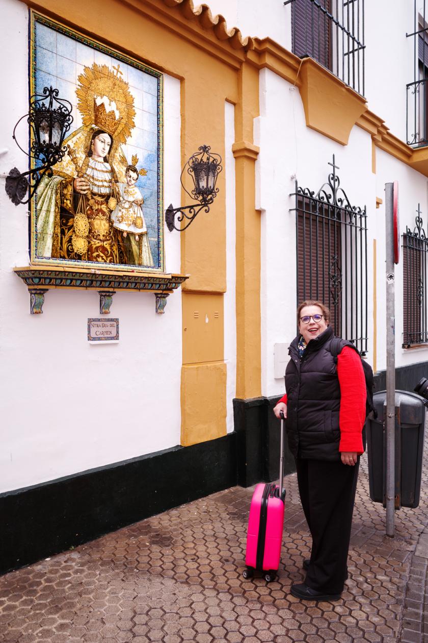 Vrouw met koffer bij beeld aan muur in steeg