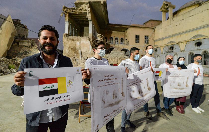 Volunteers stand holding posters welcoming Pope Francis in the ruins of the Syriac Catholic Church of the Immaculate Conception (al-Tahira) in the old city of Iraq's northern city of Mosul (formerly ravaged by Islamic State group militants) on March 2, 2021 ahead of the pontiff's visit later in the week. Zaid AL-OBEIDI / AFP Syrisch-katholieken in Mosoel pausbezoek