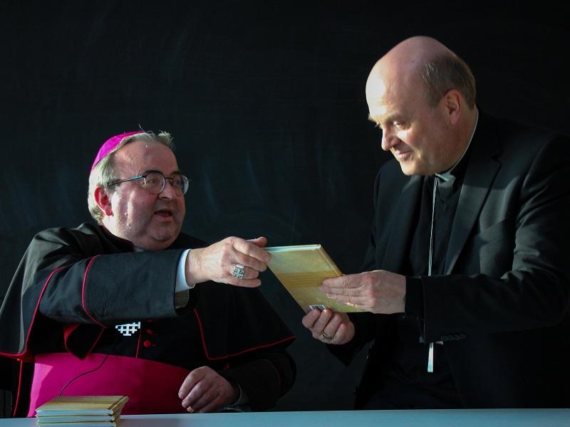 Mgr. Smeets (l) biedt 26-3-2022 het eerste exemplaar van zijn paasbundel aan aan mgr. Van den Hende, voorzitter van de Nederlandse Bischoppenconferentie. Smeets en Hende