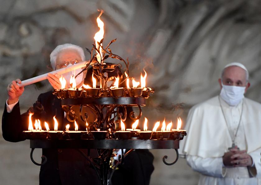 Italian President Sergio Mattarella (L) lights a candle of peace flanked by Pope Francis wearing a face masks during a ceremony for peace with representatives from various religions in Campidoglio Square in Rome on October 20, 2020. Andreas SOLARO / AFP President Mattarella ontsteekt kaars bij interreli-top op Capitool 20 okt 20