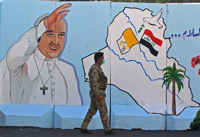 An Iraqi policeman walks by a mural depicting Pope Francis on the outer walls of Our Lady of Salvation (Sayidat al-Najat) Church, in Baghdad on February 22, 2021. Pope Francis' historic visit from March 5-8 will include trips to Baghdad, the city of Mosul in the north and a meeting with the country's top Shiite cleric Grand Ayatollah Ali Sistani. AHMAD AL-RUBAYE / AFP pausbezoek irak
