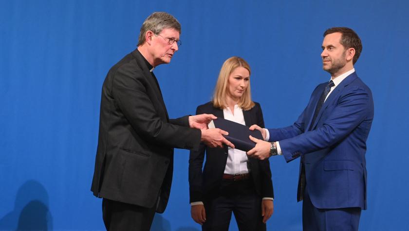 Lawyer Kerstin Stirner (C) looks on as Bjoern Gercke (R), an attorney mandated by the Church, hands over to Cologne's archbishop Rainer Maria Woelki (L) a report on abuse by clergy during a press conference on March 18, 2021 in Cologne, western Germany. Faced with accusations of trying to cover up sexual violence in Germany's most powerful Roman Catholic diocese, the archbishop of Cologne publishes the independent and long-awaited investigation. Ina Fassbender / AFP / POOL Woelki rapport seksueel misbruik
