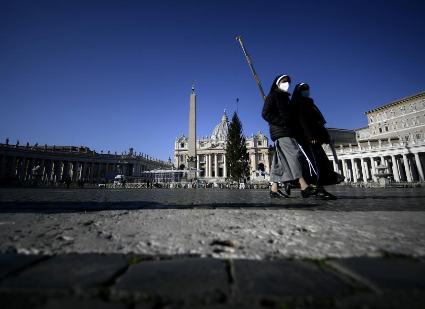 Face masked nuns walk as a crane lifts a Christmas Tree - a spruce from Kocevje, Slovenia - in St. Peter's Square, at the Vatican on November 30, 2020. Filippo MONTEFORTE / AFP Kerstboom Vaticaan corona 2020
