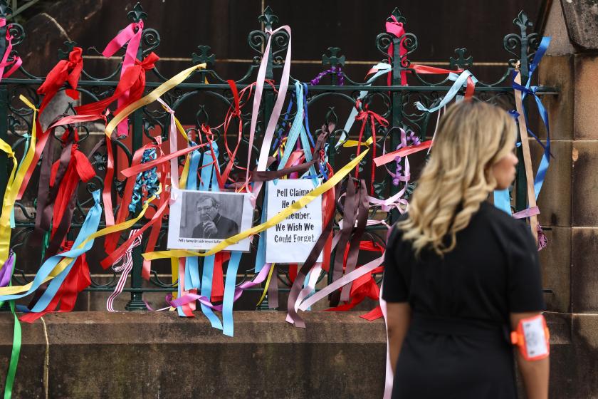 A woman looks at ribbons and banners placed by protesters on the fence surrounding St. Mary's Cathedral, where the body of Catholic Cardinal George Pell lies in state in Sydney on February 1, 2023. Pell died in Rome in January aged 81. Once considered the third most influential man in the Vatican, Pell's final years were marked by allegations of sexual abuse and criticism of his hard-line positions on abortion and gay marriage. DAVID GRAY / AFP