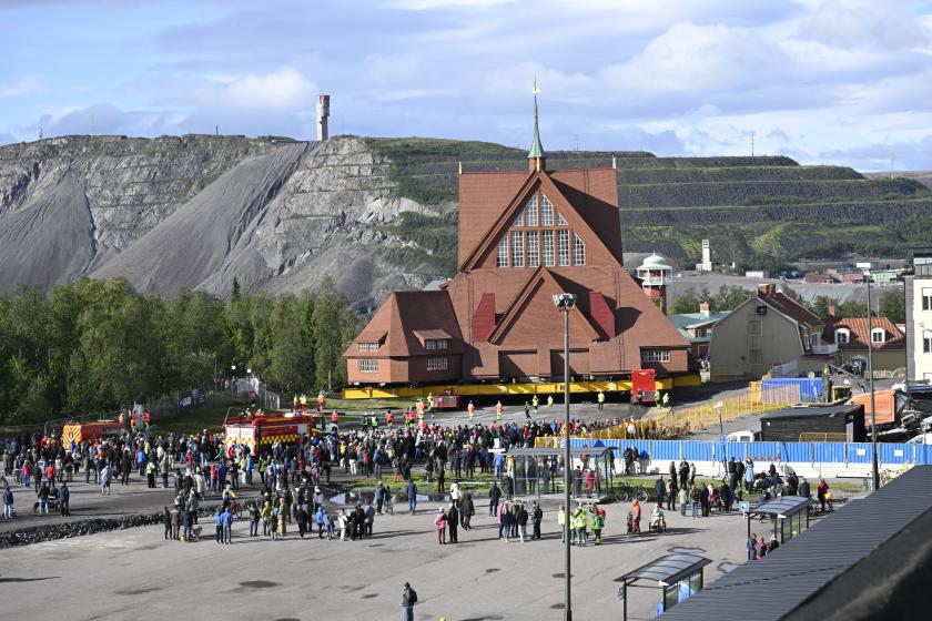 People watch as the Kiruna Church landmark is being moved on a specially designed trolley with 224 wheels at a speed of half a kilometer per hour in Kiruna, northern Sweden, 19 August 2025. The 40-meter-wide, 672,000-kilo wooden church has been placed on a wheeled trailer for its five-kilometre relocation to Kiruna's new town center on 19 and 20 August, due to the expansion of the iron ore mine. EPA/Fredrik Sandberg SWEDEN OUT