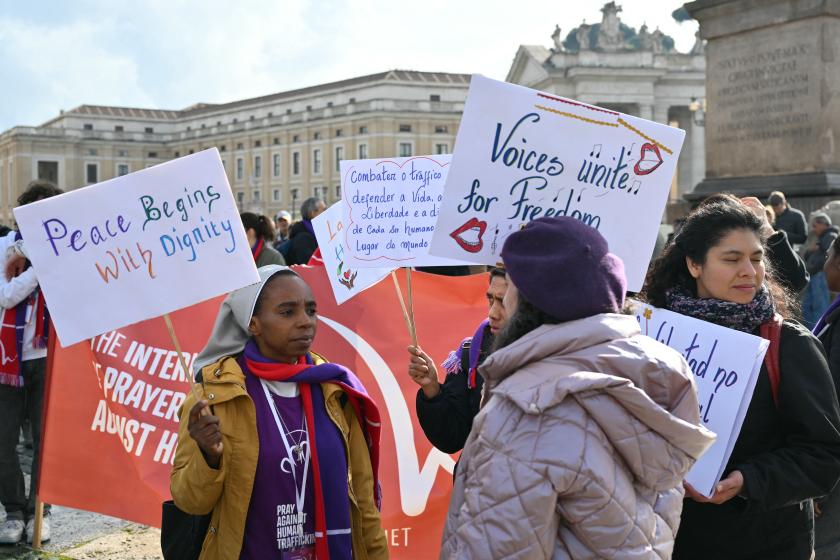 People hold placards to mark the International Day of prayer and awarness against Human Trafficking before at St. Peter's square before the Angelus prayer in The Vatican on February 8, 2026. Alberto PIZZOLI / AFP
