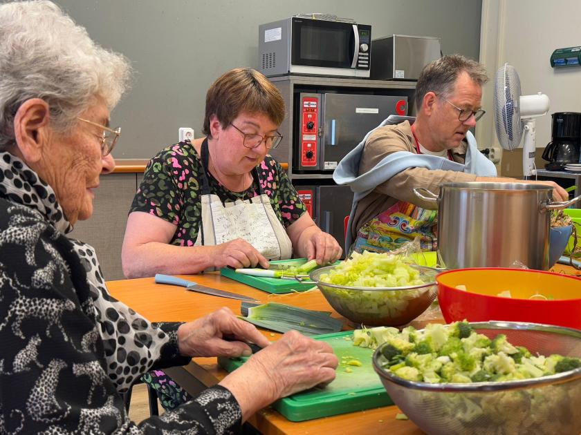 Mensen snijden groenten aan een tafel