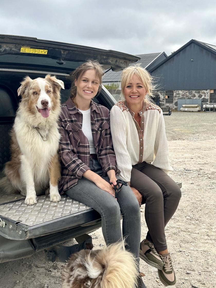 een hond en twee vrouwen zitten in de achterbak van een auto