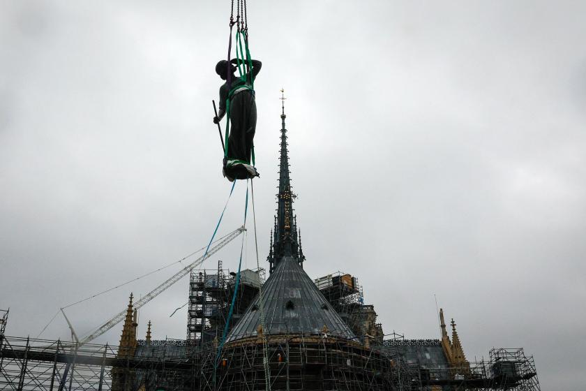 A crane lifts a statue of Saint-Thomas, the last one of the 16 giant copper-coated apostle statues, to be placed back atop the spire of Notre-Dame de Paris Cathedral in Paris on July 24, 2025. The statues, designed by Eugene Viollet-le-Duc and created by sculptor Adolphe Victor Geoffroy-Dechaume, had escaped the 2019 blaze at Notre-Dame, having been removed for renovation just days before the fire ravaged the cathedral. The statue bears the face of Eugene Viollet-le-Duc. GEOFFROY VAN DER HASSELT / AFP