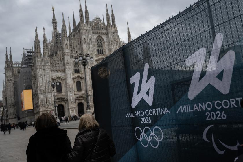 People walk past fences displaying the logo of Milano Cortina 2026 Olympic Games in Duomo’s square, in Milan on January 27, 2026.  MARCO BERTORELLO / AFP