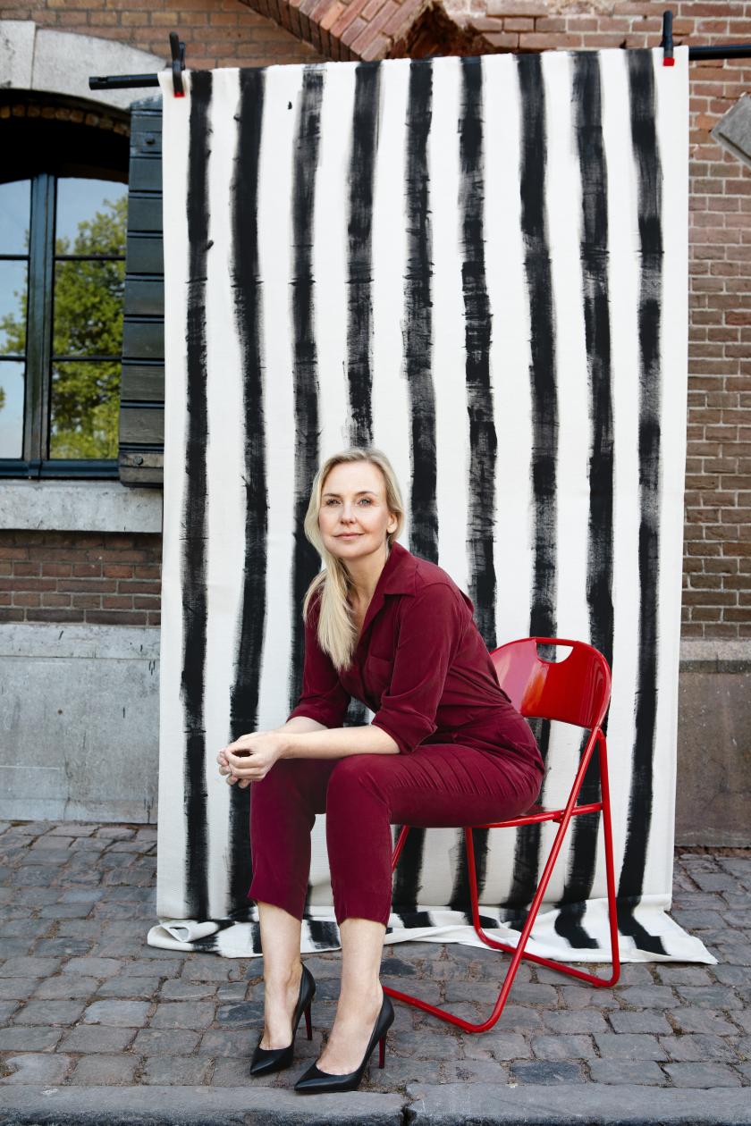 Blonde vrouw in rood pak zit voor zwart-wit-achtergrond