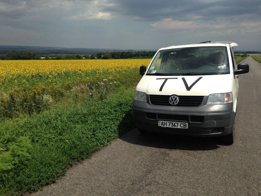 Het tv busje bij velden met zonnebloemen Het tv busje bij velden met zonnebloemen