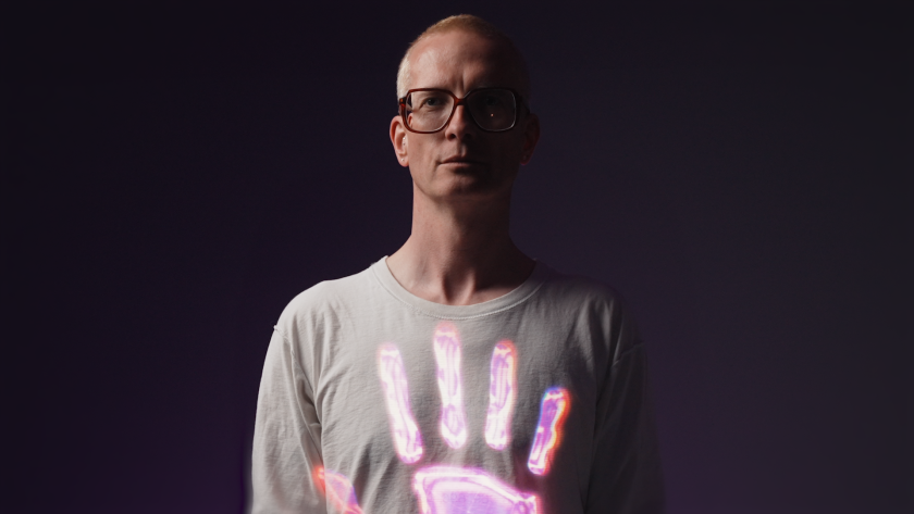 De Afghaanse hand - Bram Ieven Portret van man met bril en roze hand in het midden