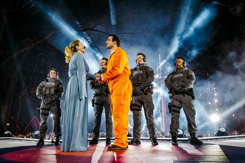 Man in oranje pak en vrouw in blauwe jurk met politieagenten
