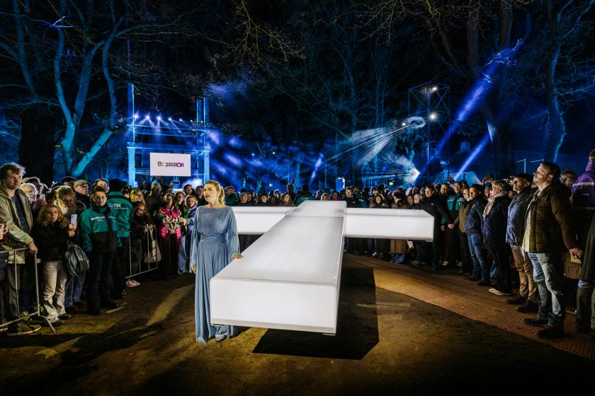 Vrouw in blauwe jurk naast wit kruis