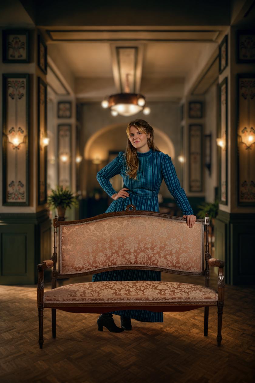 Een vrouw in een blauwe jurk poseert in een luxe hotel