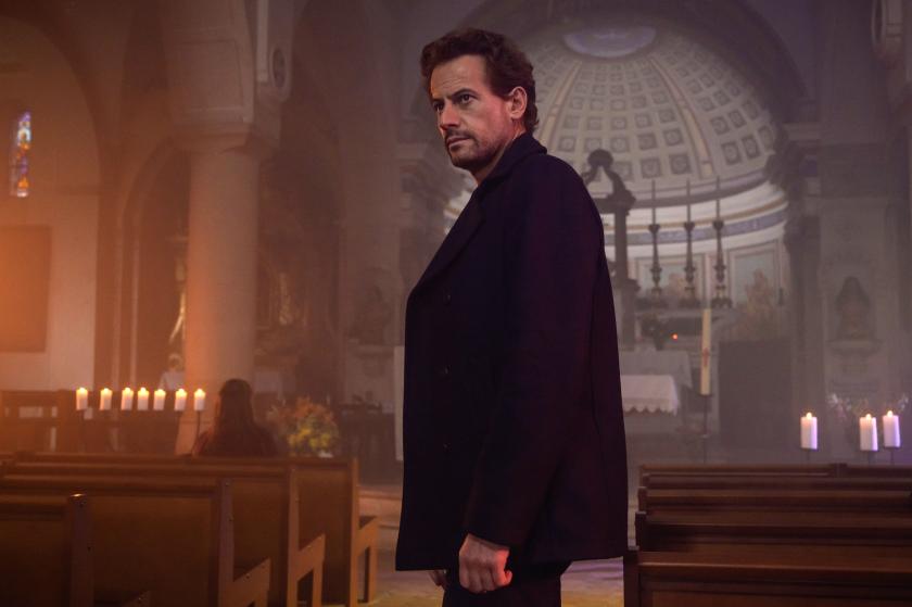 The Reunion Man staat in een kerk kijkt naast schuin langs de kamera.