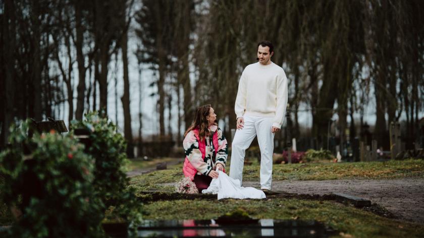 Man in witte kleding en vrouw bij graf
