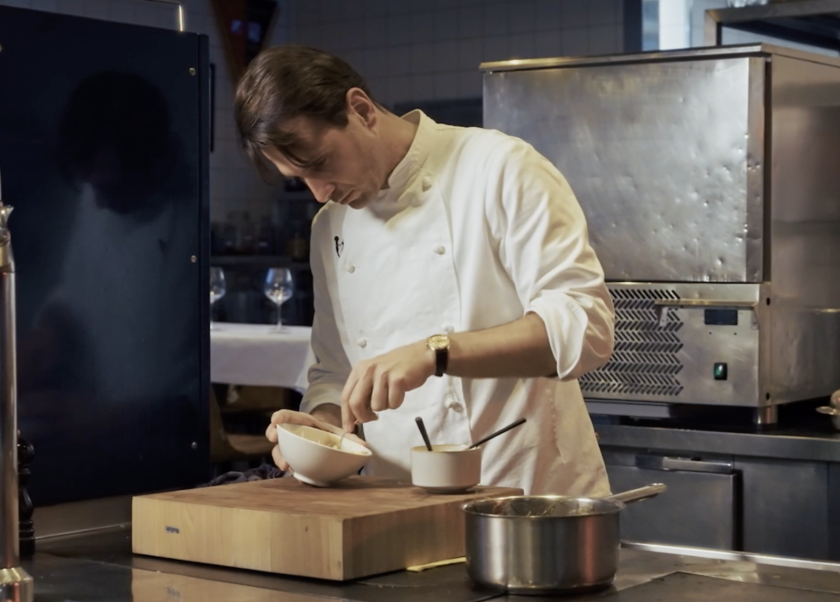 man in witte kleding aan het koken