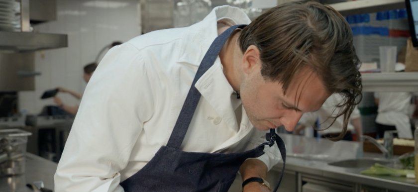 Man met schort in keuken kijkend naar beneden