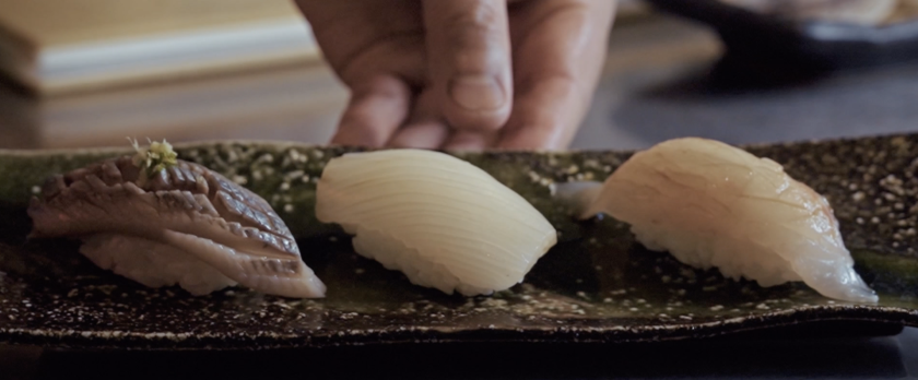 Hand houdt plaat met sushi vast