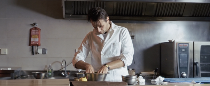 Man in witte jas in keuken aan het koken