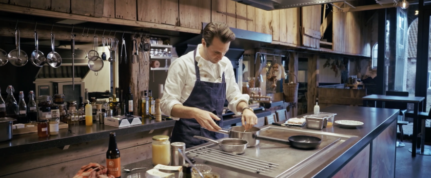 Man met schort in keuken roerend in pan