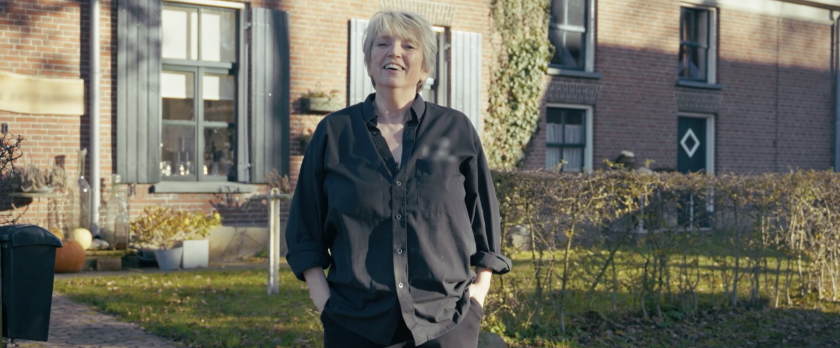 Vrouw in zwarte blouse voor een huis