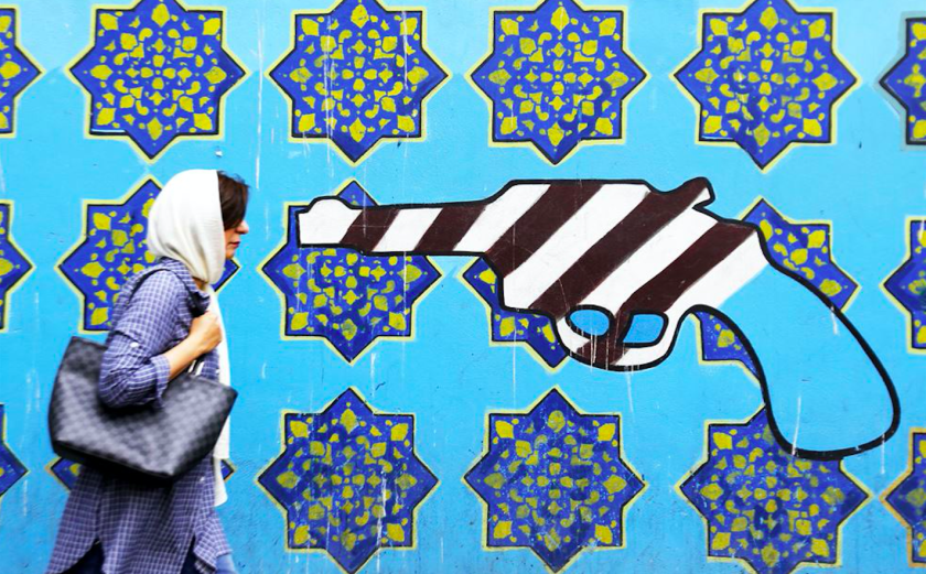 Vrouw loopt langs een muurschildering op de voormalige Amerikaanse ambassade in Teheran