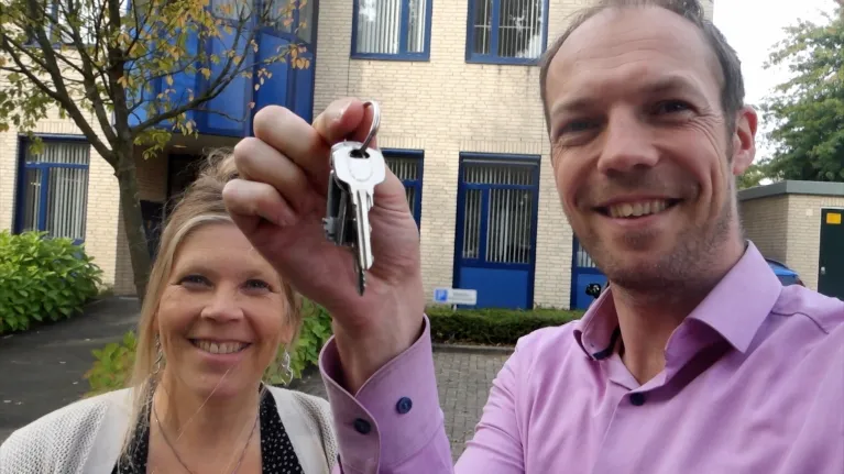 Man en vrouw blij met sleutel omhoog