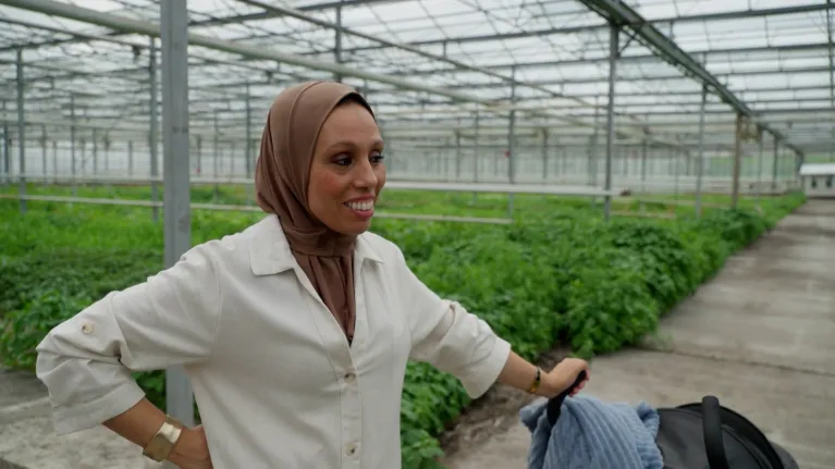 Vrouw met kinderwagen in groene kas
