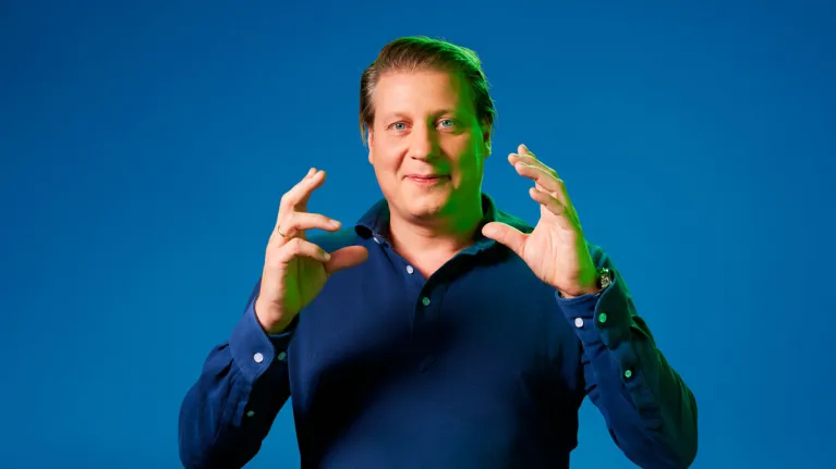 Leon Mazairac poseert voor een blauwe achtergrond in een blauwe trui