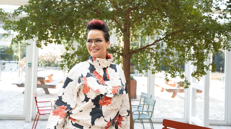 Mevrouw met bloemenprint shirt voor een boom