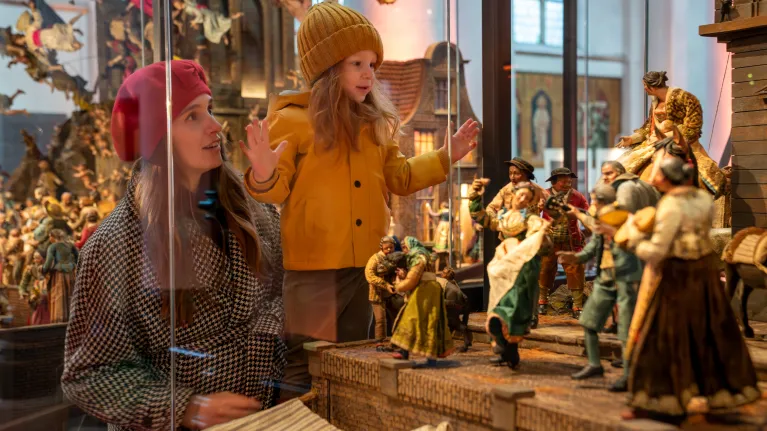 Meisje en vrouw kijken naar kerststal