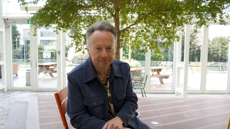 Man met grijs haar op een stoel onder een boom