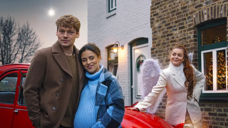 twee personen en een engel voor een rode auto