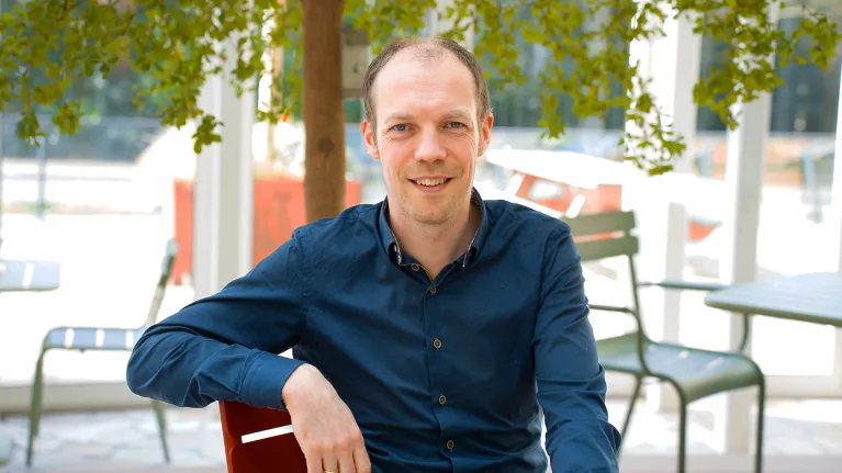 Meneer met blauw overhemd onder een boom