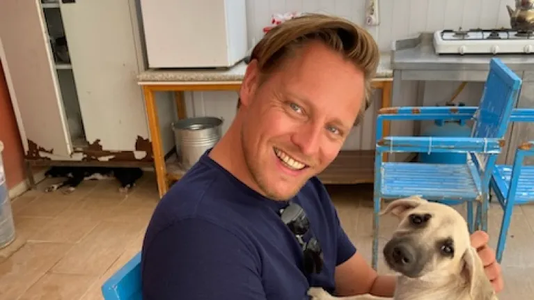 Lachende man op stoel met hond op schoot