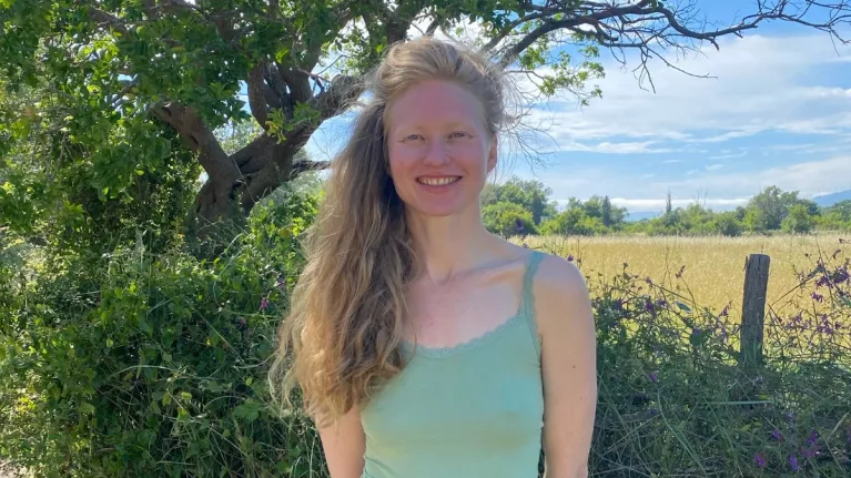 Vrouw met topje lachend voor heg