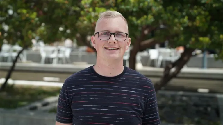 Man met bril lachend in camera met zwart shirt