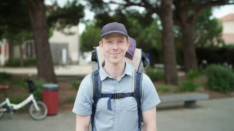 Man met pet en rugzak in blauwe blouse met korte mouwen