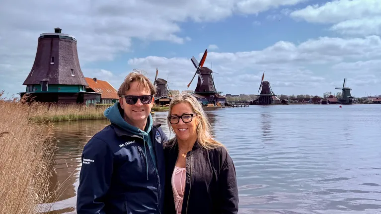 Man en vrouw staan naast elkaar voor Hollandse molens