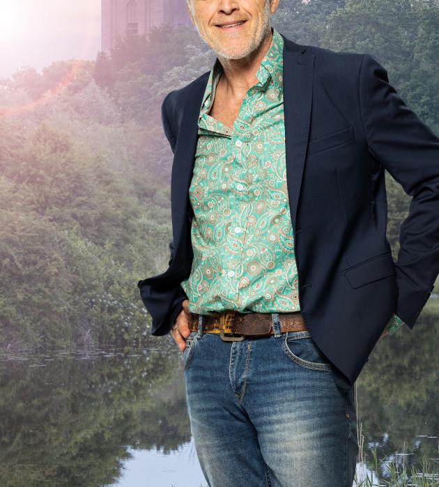 Zin in morgen- Stef Bos Zin in morgen - Stef Bos met jeansbroek, groen overhemd, zwart jasje voor een kerktoren in het ochtendlicht