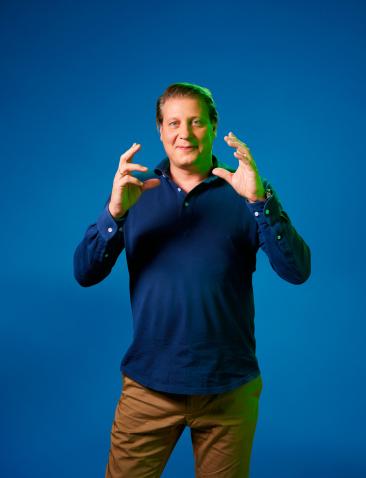 Leon Mazairac poseert voor een blauwe achtergrond in een blauwe trui