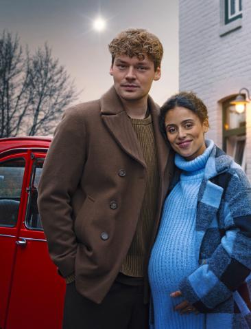 twee personen en een engel voor een rode auto